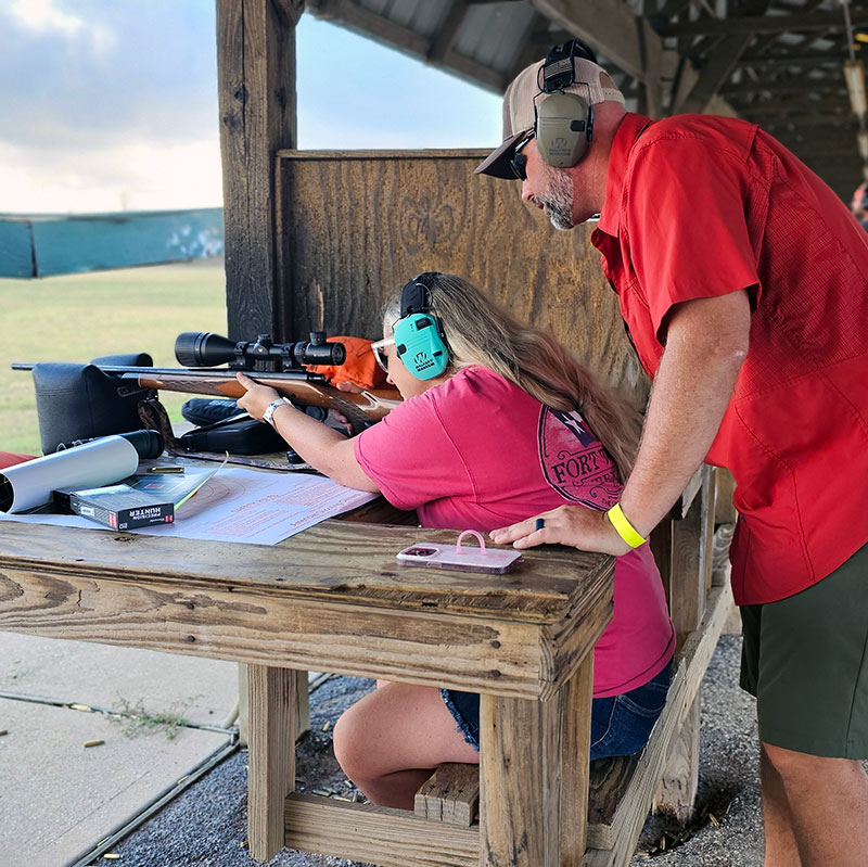 Dad teaching daughter how to shoot.